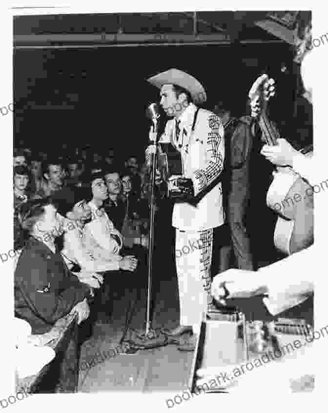 A Black And White Photo Of Hank Williams Playing Guitar And Singing Into A Microphone. Lovesick Blues: The Life Of Hank Williams